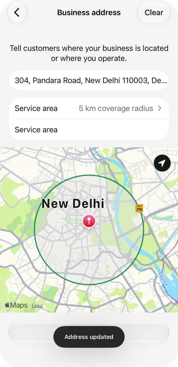 Business address screen with a full address, a Service area of 5 km coverage radius, a circle on the map and the message Address updated