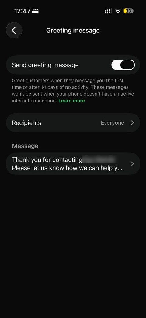 WhatsApp Business greeting message settings, with the toggle on and an example message